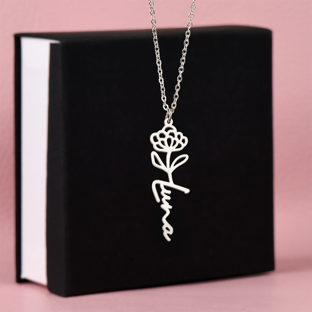 Silver-tone Luna birth flower name necklace displayed on a black gift box.