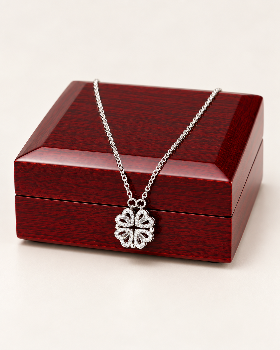 Silver-tone magnetic hearts clover necklace draped across a wooden gift box.