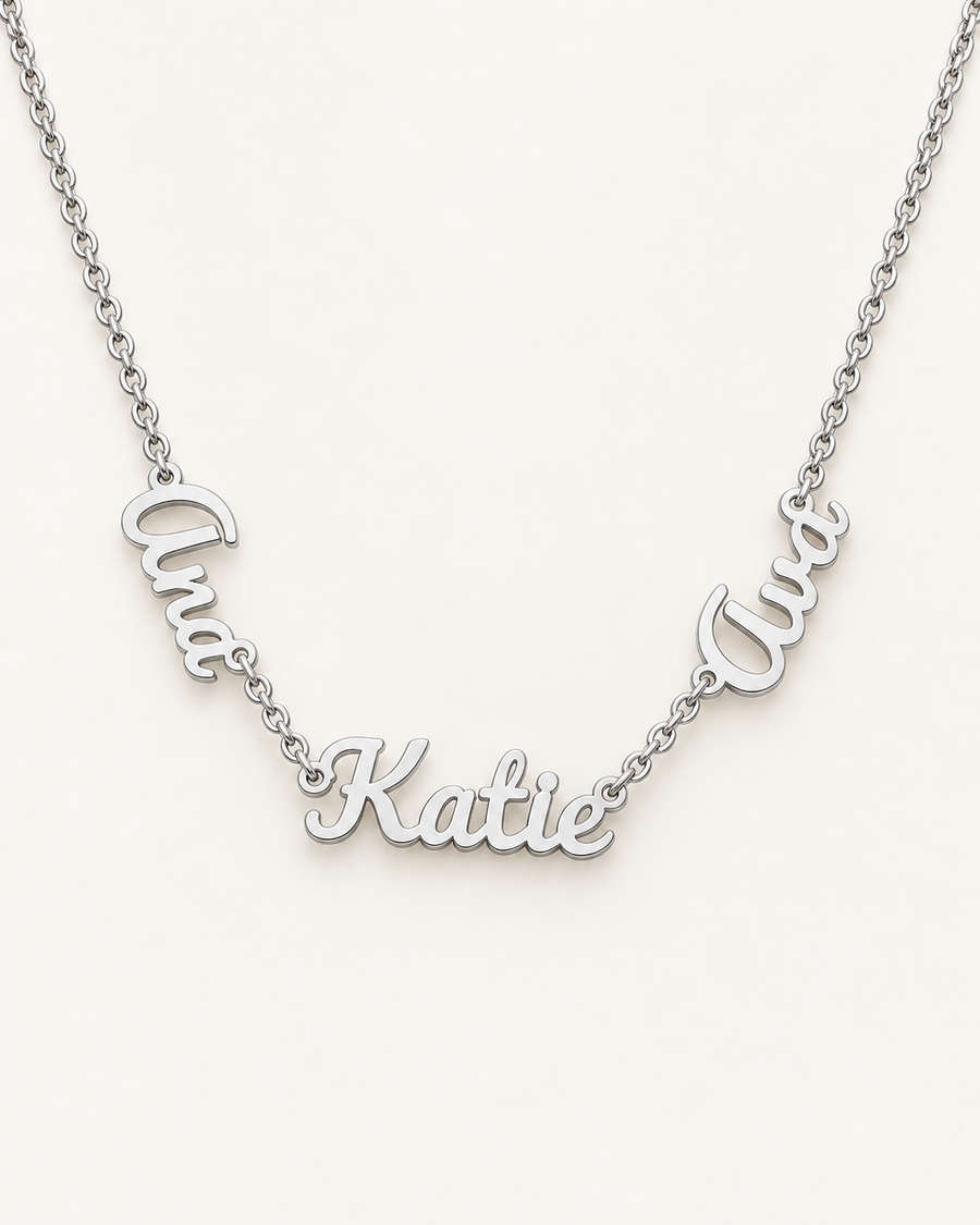 Silver-tone necklace with three connected script name pendants on an ivory background.