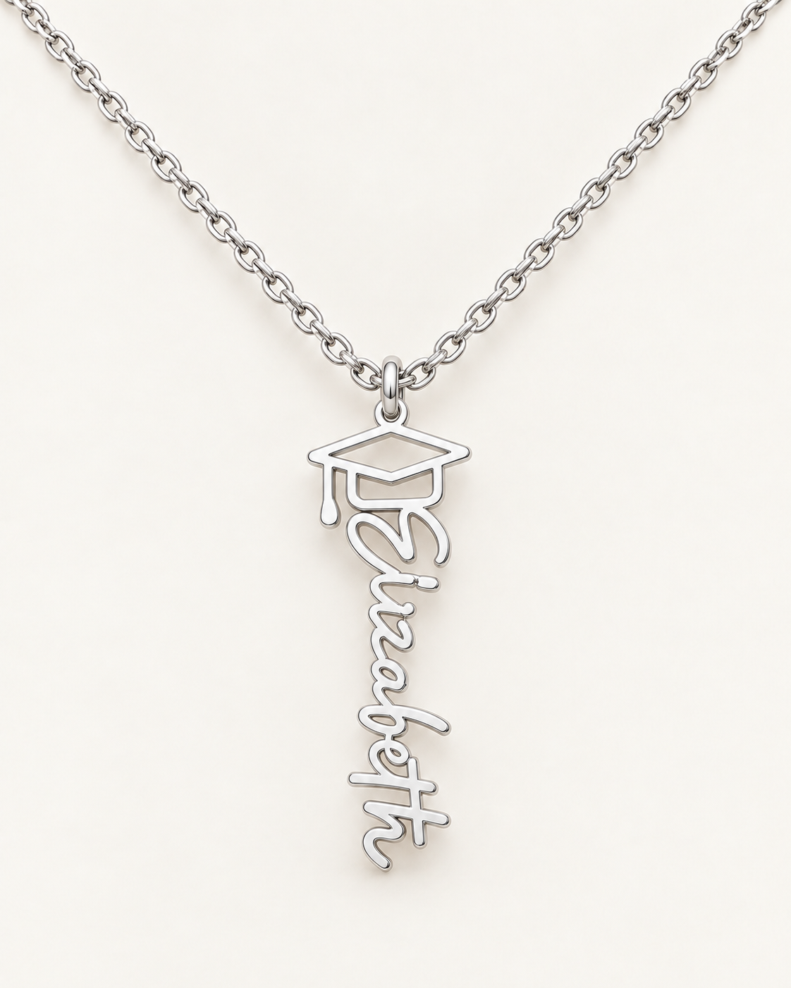 Silver-tone vertical Elizabeth name necklace topped with a graduation cap motif on ivory.