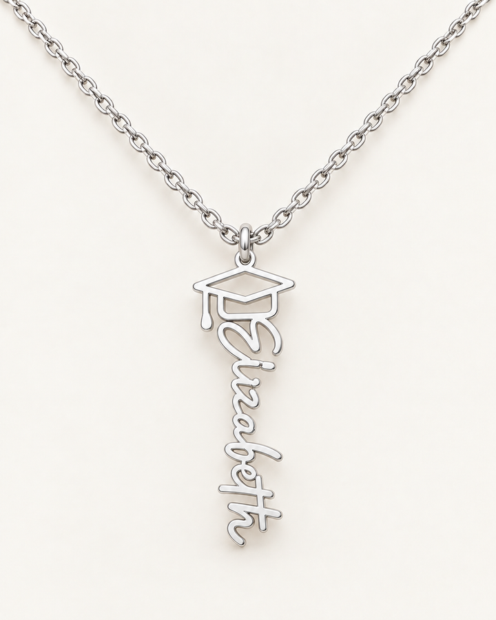 Silver-tone vertical Elizabeth name necklace topped with a graduation cap motif on ivory.
