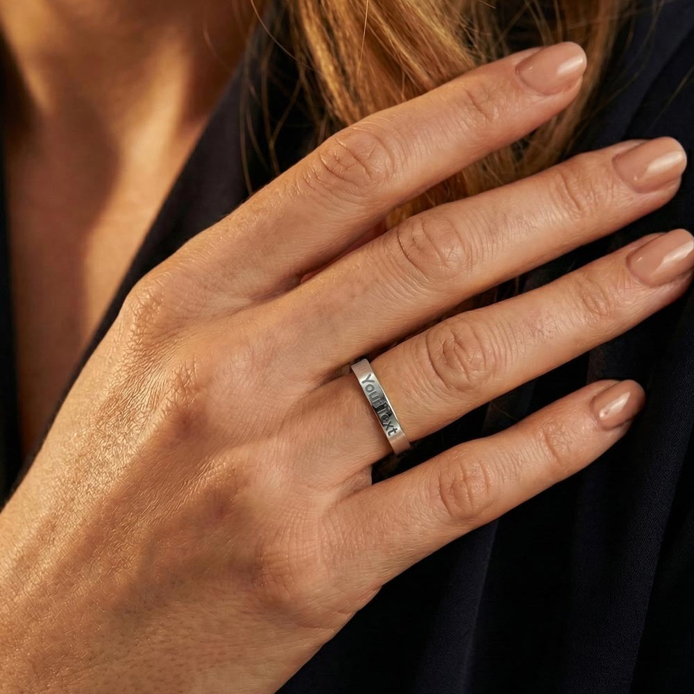 Close-up of a slim silver-tone engraved ring on a woman's hand.