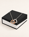 Two-tone interlocking hearts necklace displayed on a black gift box.