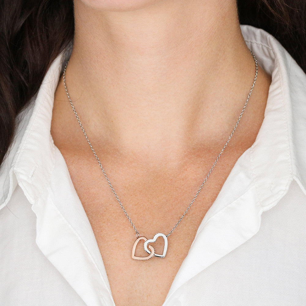 Woman wearing a two-tone interlocking hearts necklace with a white shirt.