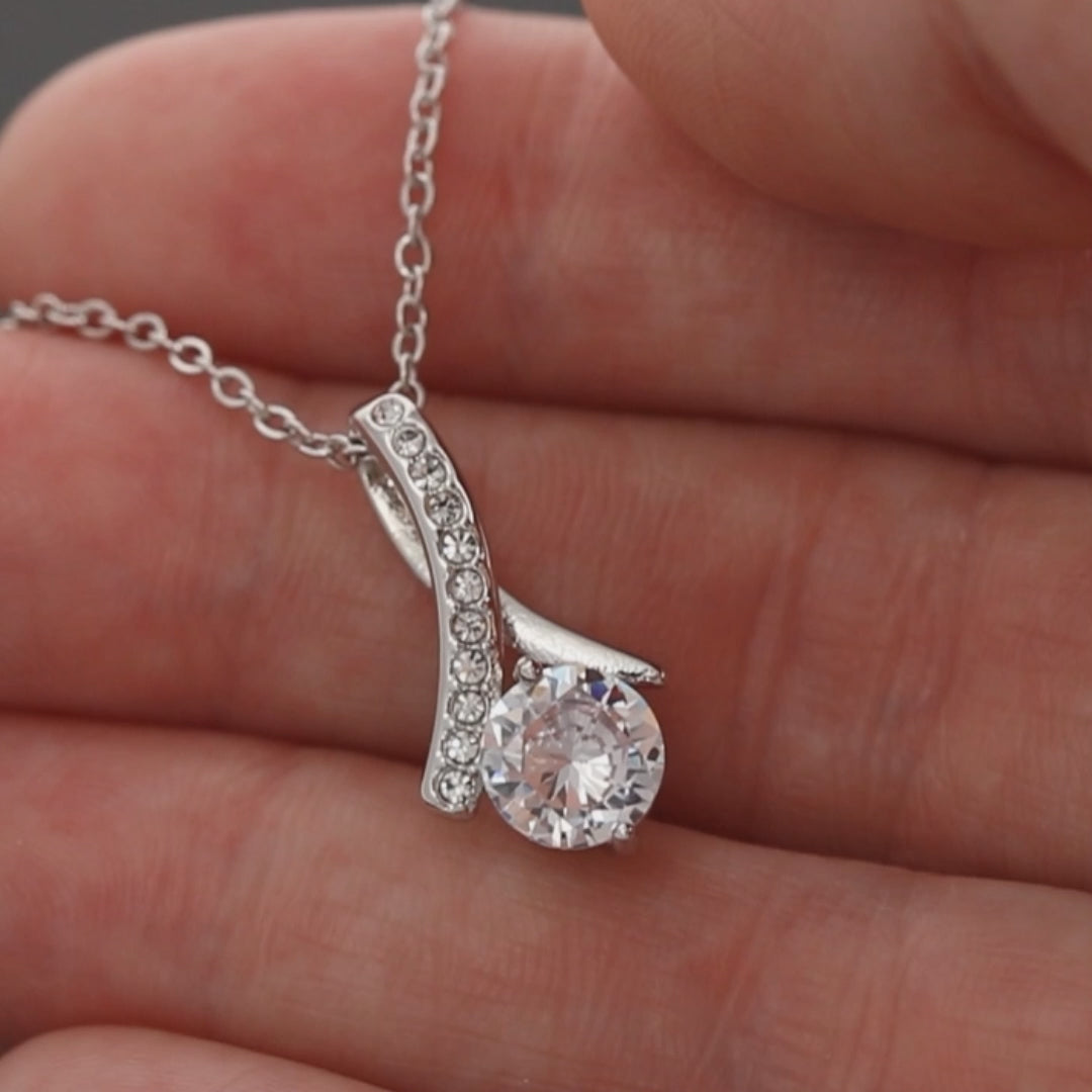 Product video showing the silver-tone ribbon CZ pendant against a hand.